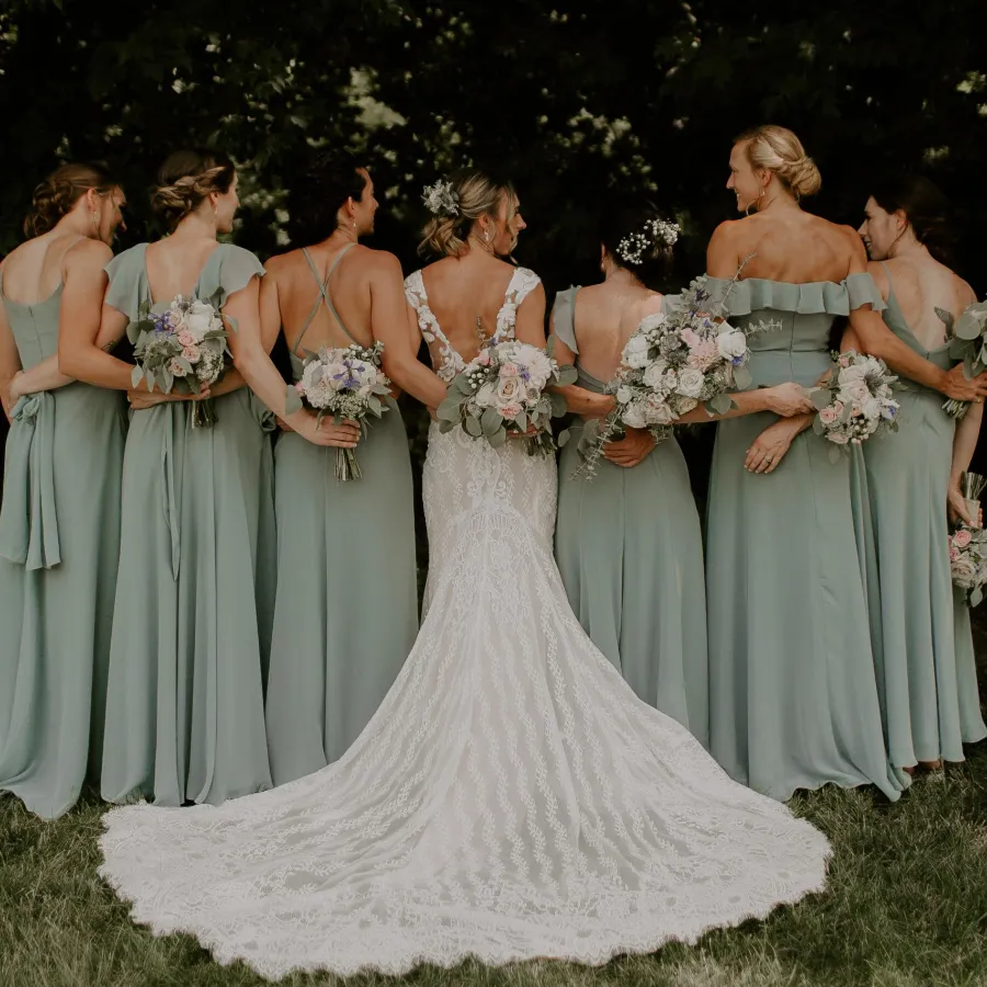 Bride and bridesmaids posing with backs to camera at Briar Barns historic wedding venue Sparta Michigan