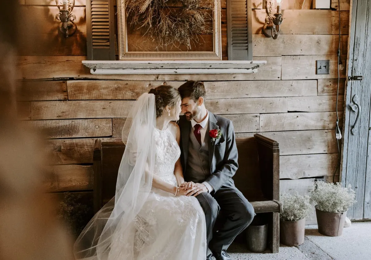 Bride and groom sitting on a bench staring into eachothers eyes at briar barns event space