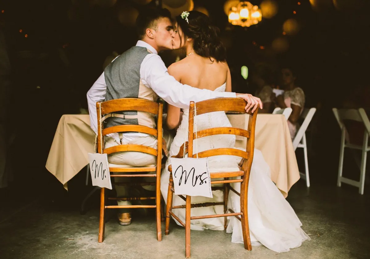 Bride and groom kissing at reception table inside Briar Barns historic barn wedding venue Sparta Michigan