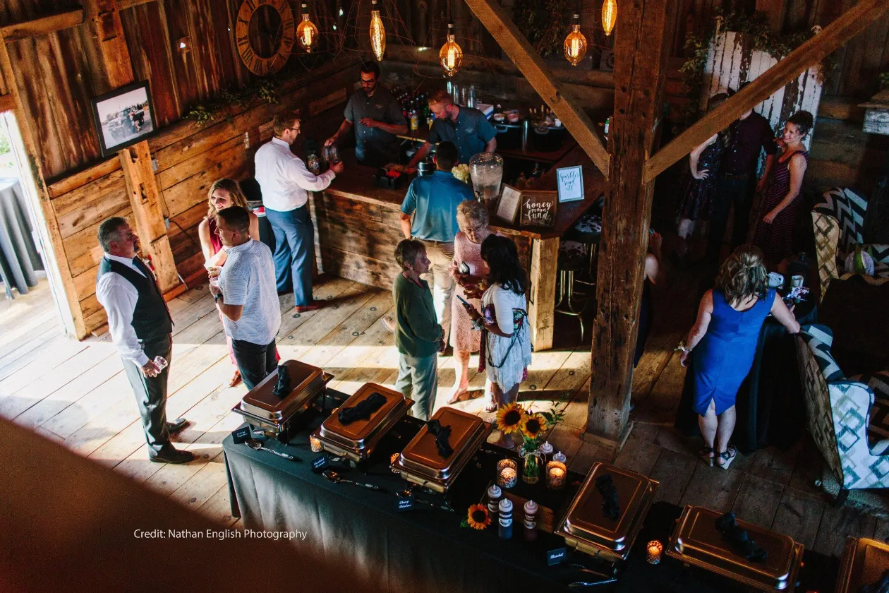 Wedding guests socializing inside historic barn at Briar Barns wedding venue Sparta Michigan