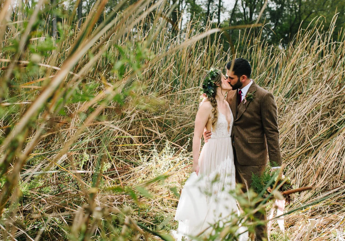 Bride and groom kissing in tall grass at historic Briar Barns wedding venue Sparta Michigan