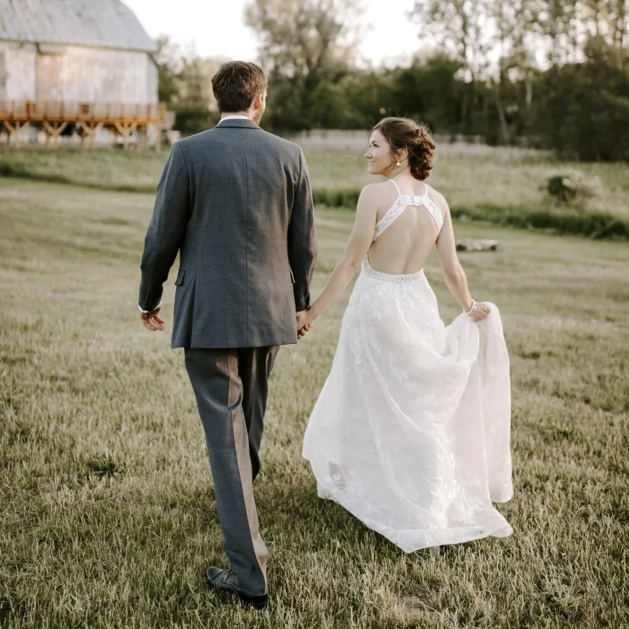 Bride and groom walking through field at Briar Barns historic wedding venue Sparta Michigan
